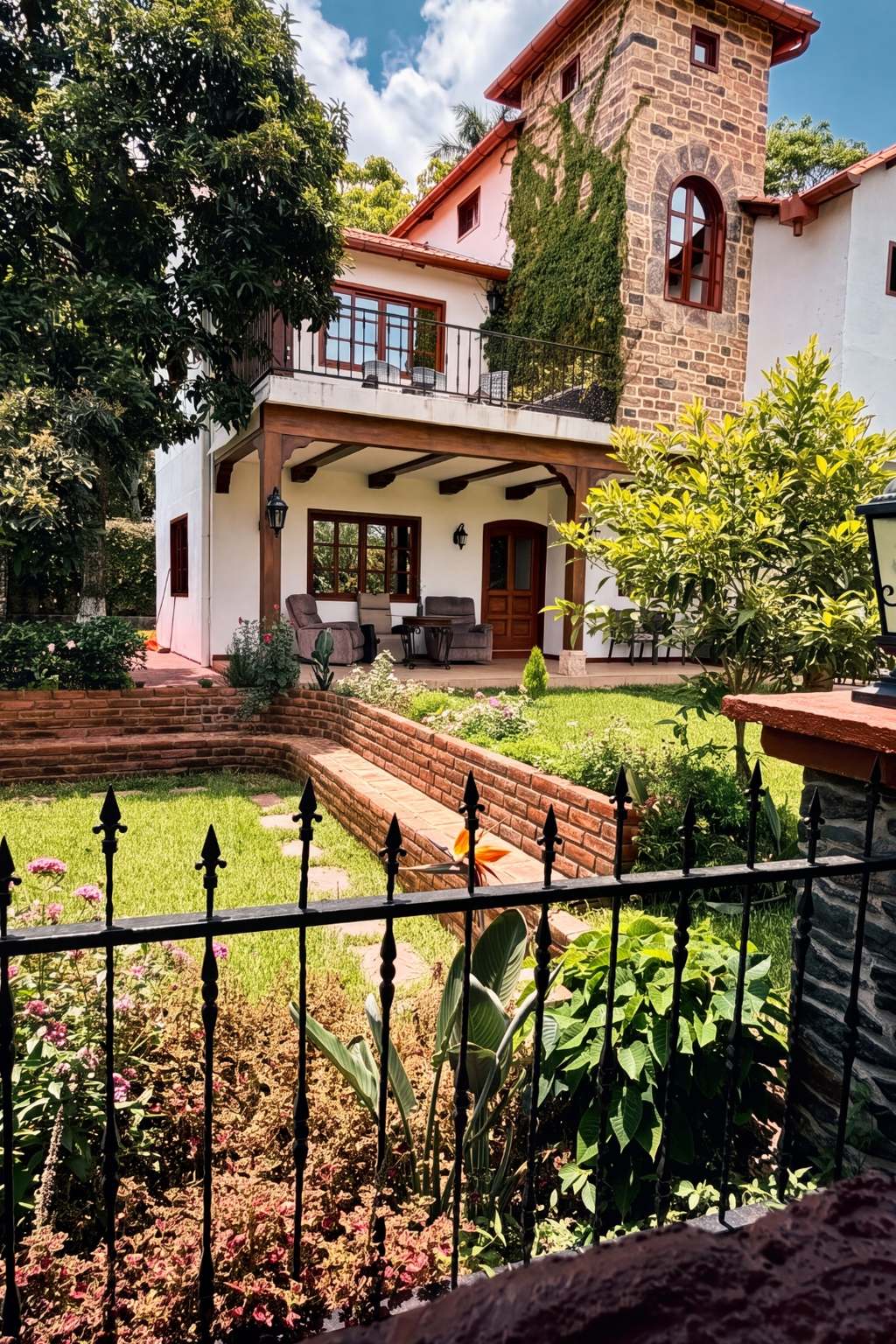 Fachada de la villa con torre de piedra cubierta de hiedra y terraza cubierta